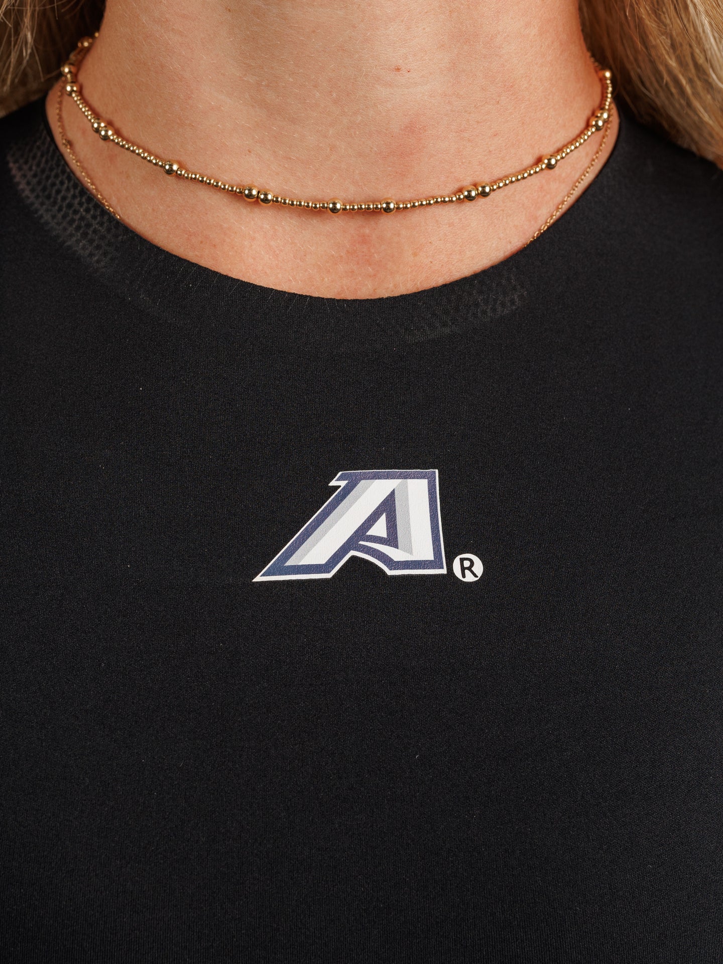 Arena Graffiti women's high neck padded active top with "A" logo, designed for sports and athletic wear.