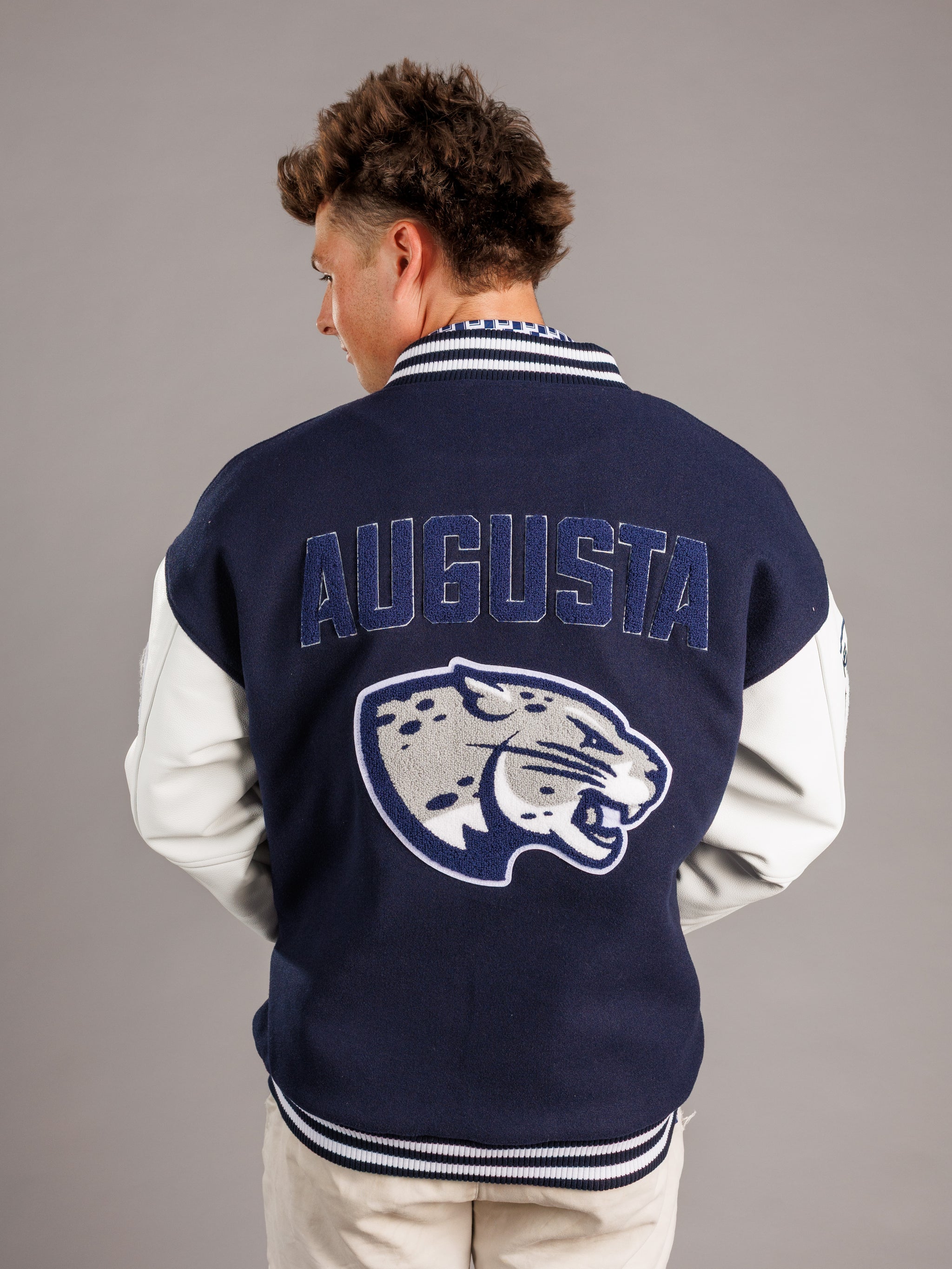 Arena Graffiti Augusta University men's varsity Jag letterman jacket with team patches and leather sleeves, front view.